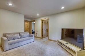 Un salon comprenant un canapé, un téléviseur à écran plat et un meuble de rangement en bois.