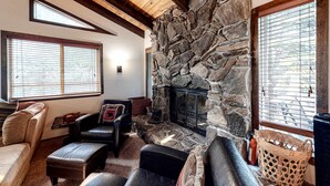 A living room with a stone fireplace, leather furniture, and large windows. - Beautiful cabin near hiking, biking, skiing, Heavenly Valley with fireplace (South Lake Tahoe)