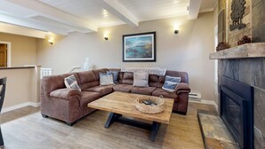 A living room with a brown sectional sofa, a wooden coffee table, a fireplace, and a painting on the wall. - Cozy Condo with Tennis, Fireplace, & BBQ in Incline Village (Incline Village)