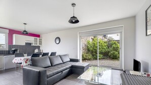 A modern kitchen with a dining area, a black leather sofa, and a glass coffee table.
