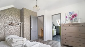 A bedroom with a bed, a dresser, a mirror, and a door leading to another room.