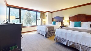 Une chambre d’hôtel avec deux lits, un bureau et de grandes fenêtres.