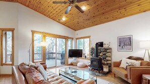 Una sala de estar acogedora con un sofá de cuero, una mesa de centro de vidrio, una chimenea y un televisor.