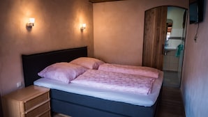 A bedroom with a bed, bedside tables, and a wooden door leading to a bathroom. - Guest House 'Heuhof-Breiau Gästedoppelzimmer' with Shared Terrace, Shared Garden and Wi-Fi (Sontra)