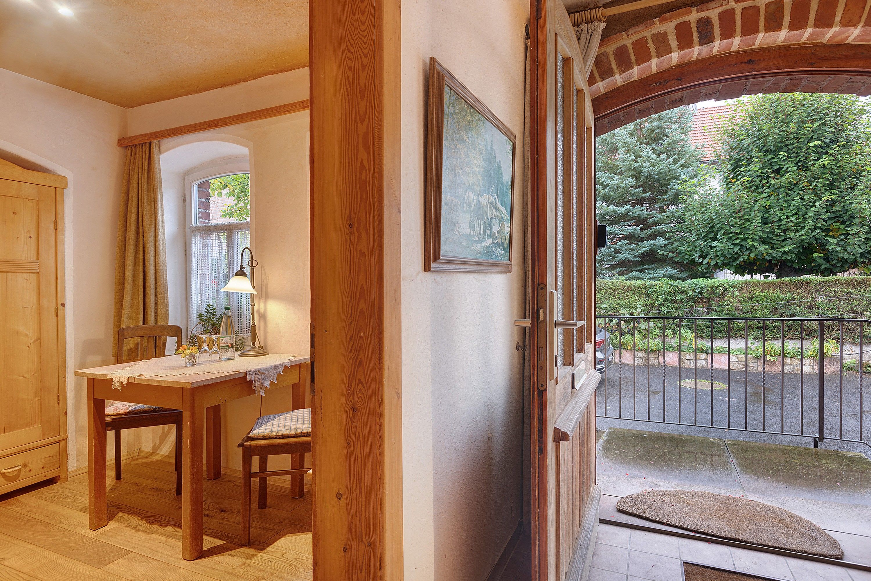 Un interior de madera con zona de comedor, una puerta que da al exterior y vistas a un jardín.