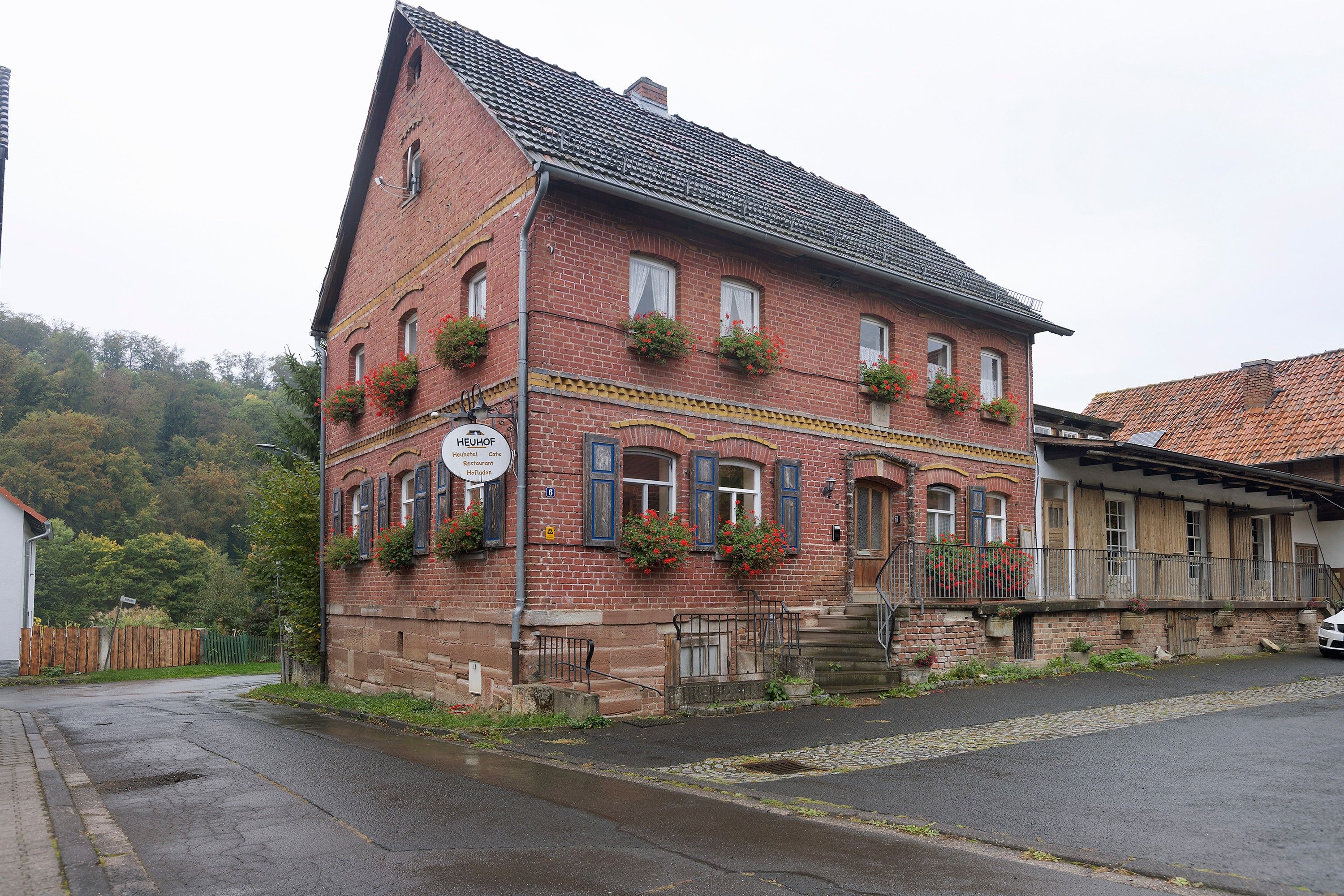 Ein rotbacksteiner Gebäude mit steilem Dach, zahlreichen Fenstern und Blumenkästen im zweiten Stock.