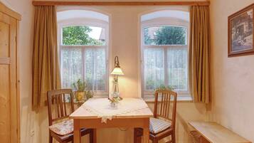 Un coin repas comprenant une table, deux chaises, un banc et une lampe.