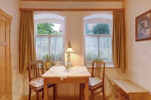 Un coin repas comprenant une table, deux chaises, un banc et une lampe.