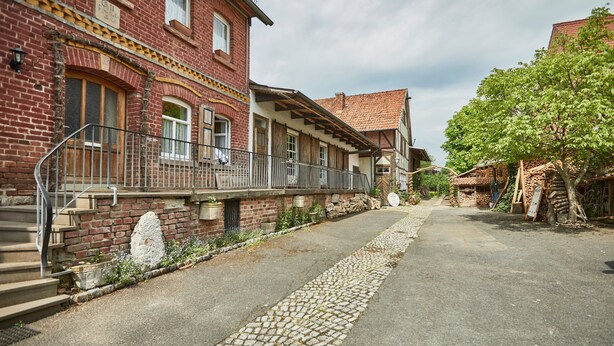 A traditional European-style building with a cobblestone street, a wooden staircase, and a brick facade. - Guest House 'Heuhof-Breiau Gästedoppelzimmer' with Shared Terrace, Shared Garden and Wi-Fi (Sontra)