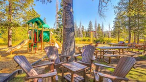 Un parco con sedie in legno di tipo Adirondack, tavoli da picnic e un’area giochi.
