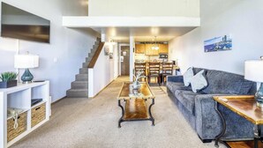 Ein modernes Wohnzimmer mit Sofa, Couchtisch und einer Treppe, die in eine Küche führt.