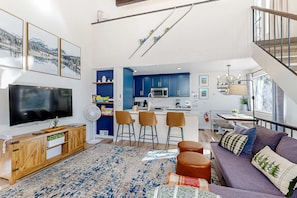 Ein modernes Wohnzimmer mit großem Fernseher, einer Holz-Unterhaltungseinrichtung und einem violetten Sofa.
