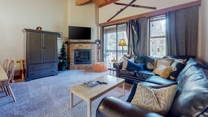 Una sala de estar con chimenea, sofá de cuero y televisor.