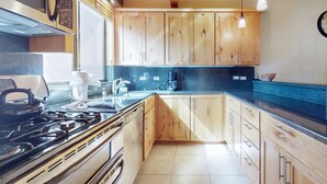 Una cocina con armarios de madera, estufa y cafetera.