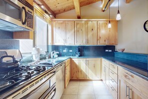 A kitchen with wooden cabinets, a stove, and a coffee maker. - near Kings Beach & Northstar Village with balcony (Northstar - Truckee)