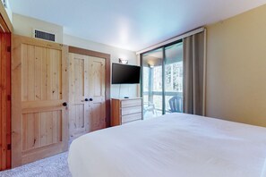 Ein Schlafzimmer mit einem großen Bett, einem Fernseher, einer Schiebetür und einem Holzschrank.