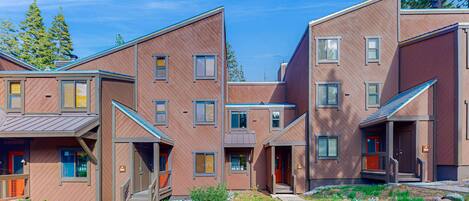 Un immeuble résidentiel moderne à plusieurs étages, doté d’une cour intérieure, de balcons et d’une variété de styles de fenêtres.