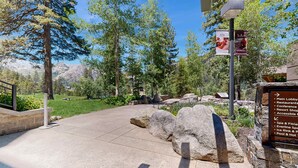 A paved pathway leading to a building with a sign listing amenities including a spa, restaurants, and a pool. - Everline Resort & Spa - ski-in&ski-out studio, pools, ice rink, gym, & tennis (Olympic Valley)