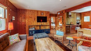 Interior acolhedor de uma cabana, com sala de estar, área de jantar e cozinha.