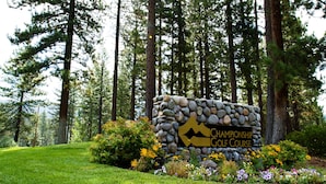 En stenskilte med teksten 'Championship Golf Course', omgivet af grøn bevoksning og blomster.