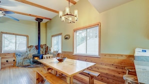 Una cabaña acogedora con interior de madera, una pared de piedra, chimenea y zona de comedor con bancos.