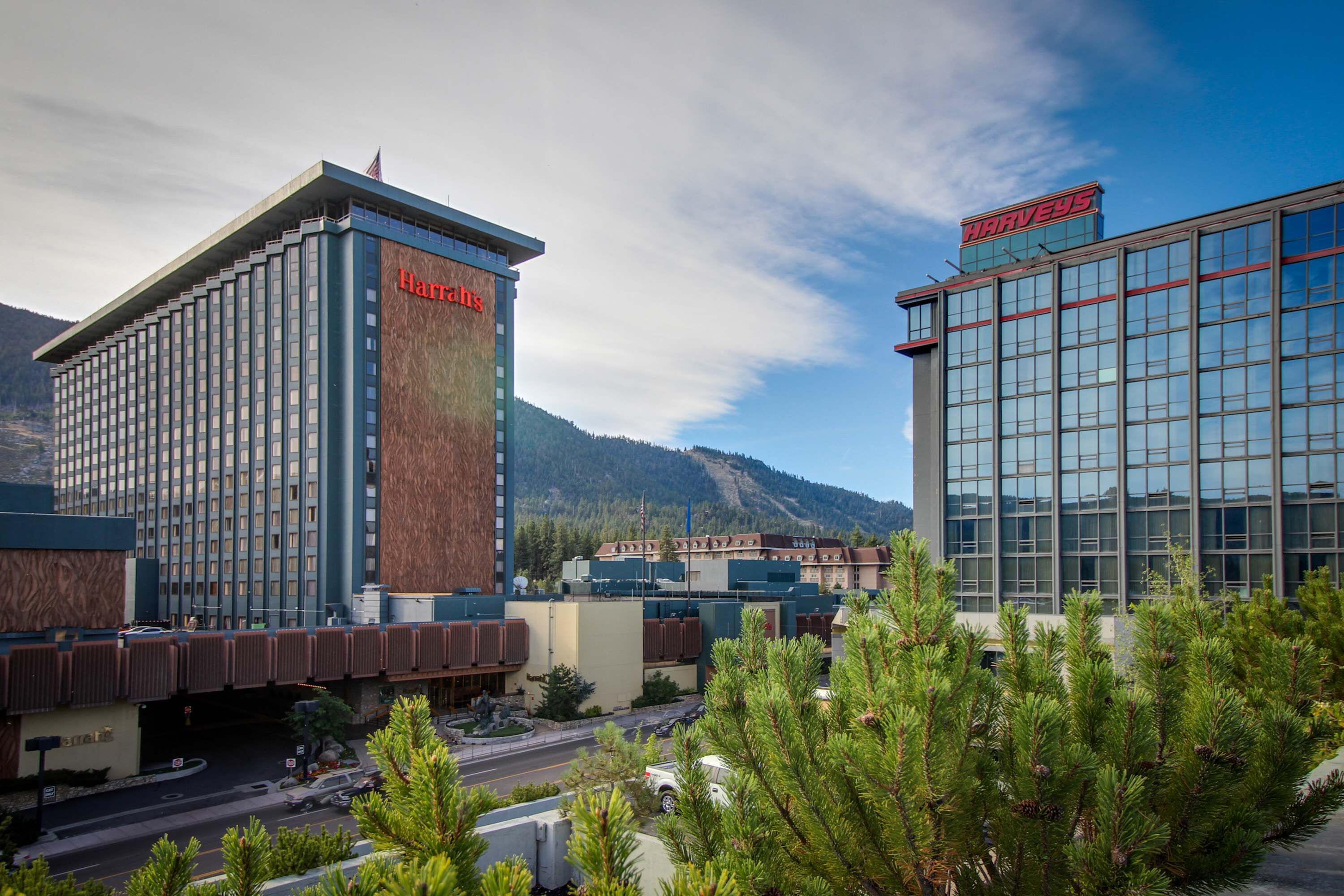 A hotel with a prominent 'Harveys' sign, a modern building with a large glass facade, and a mountainous backdrop.