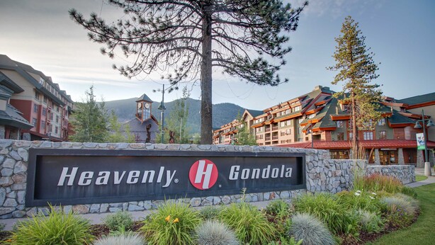 Letrero de 'Heavenly Gondola' con un muro de piedra y jardín ajardinado.