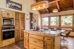 A kitchen with wooden cabinets, a built-in oven, and a central island with a kettle. - Woodland dog-friendly home minutes to the beach with wood fireplace, sleeps 10 (Zephyr Cove)