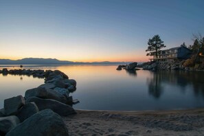 A lakeside property with a large house, rocky shoreline, and a calm water body. - Woodland dog-friendly home minutes to the beach with wood fireplace, sleeps 10 (Zephyr Cove)