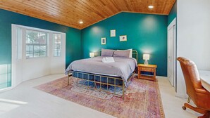 A bedroom with a wooden ceiling, teal walls, a bed with a patterned rug, bedside lamps, and a chair. - Spacious home with a pool table close to golf, skiing, hiking & biking (South Lake Tahoe)