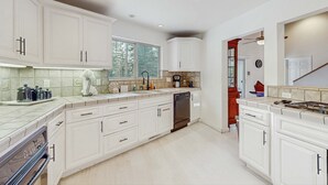 A modern kitchen with white cabinetry, a built-in oven, and a dishwasher. - Spacious home with a pool table close to golf, skiing, hiking & biking (South Lake Tahoe)