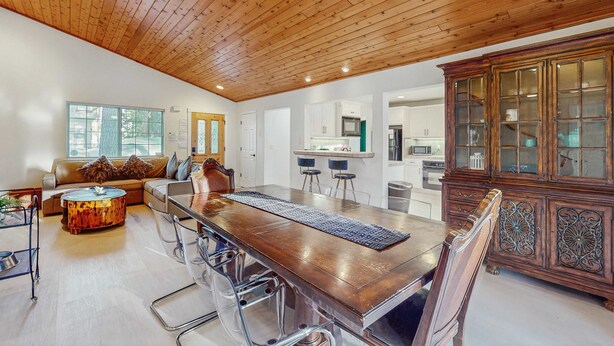 A spacious room with a long wooden dining table, a sofa, and a cabinet with glass doors. - Spacious home with a pool table close to golf, skiing, hiking & biking (South Lake Tahoe)