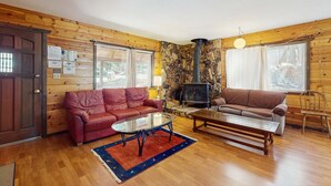 Una sala de estar acogedora con paredes de madera, una chimenea de piedra, dos sofás y una mesa de centro.