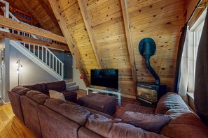 A loft-style living room with a wooden ceiling, a television, a fireplace, and a staircase. - Tranquil Family-Friendly A-Frame Cabin with Big Backyard, Deck, & Gas Grill (South Lake Tahoe)