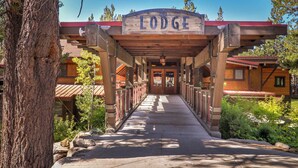 L'ingresso di un lodge con un cartello di legno, una tettoia e un edificio con tetto rosso.