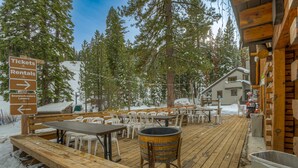 A wooden deck with tables and chairs, a barrel, and a sign for tickets and rentals. - Ski-in/ski-out townhome with fireplace, pool, hot tub & on-site ski/sled hill (Tahoe City)