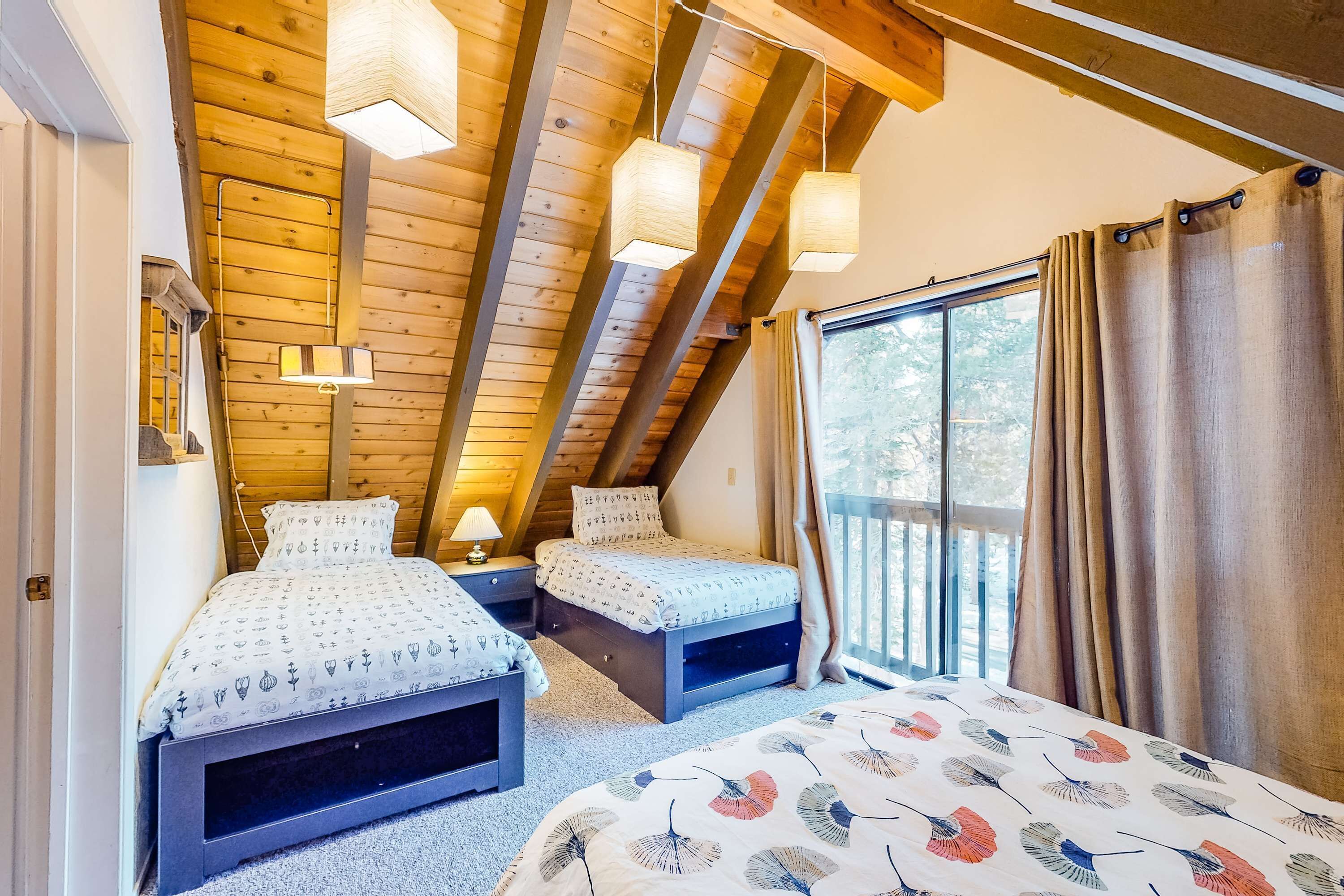 A bedroom with two beds, wooden ceiling beams, and a large window with curtains.