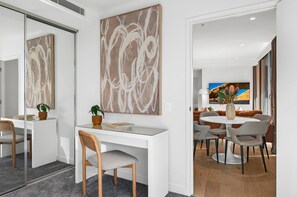 A modern office space with a white desk, grey chairs, and a large abstract painting. - Modern Apartment With Stunning Views in Southbank (Melbourne)