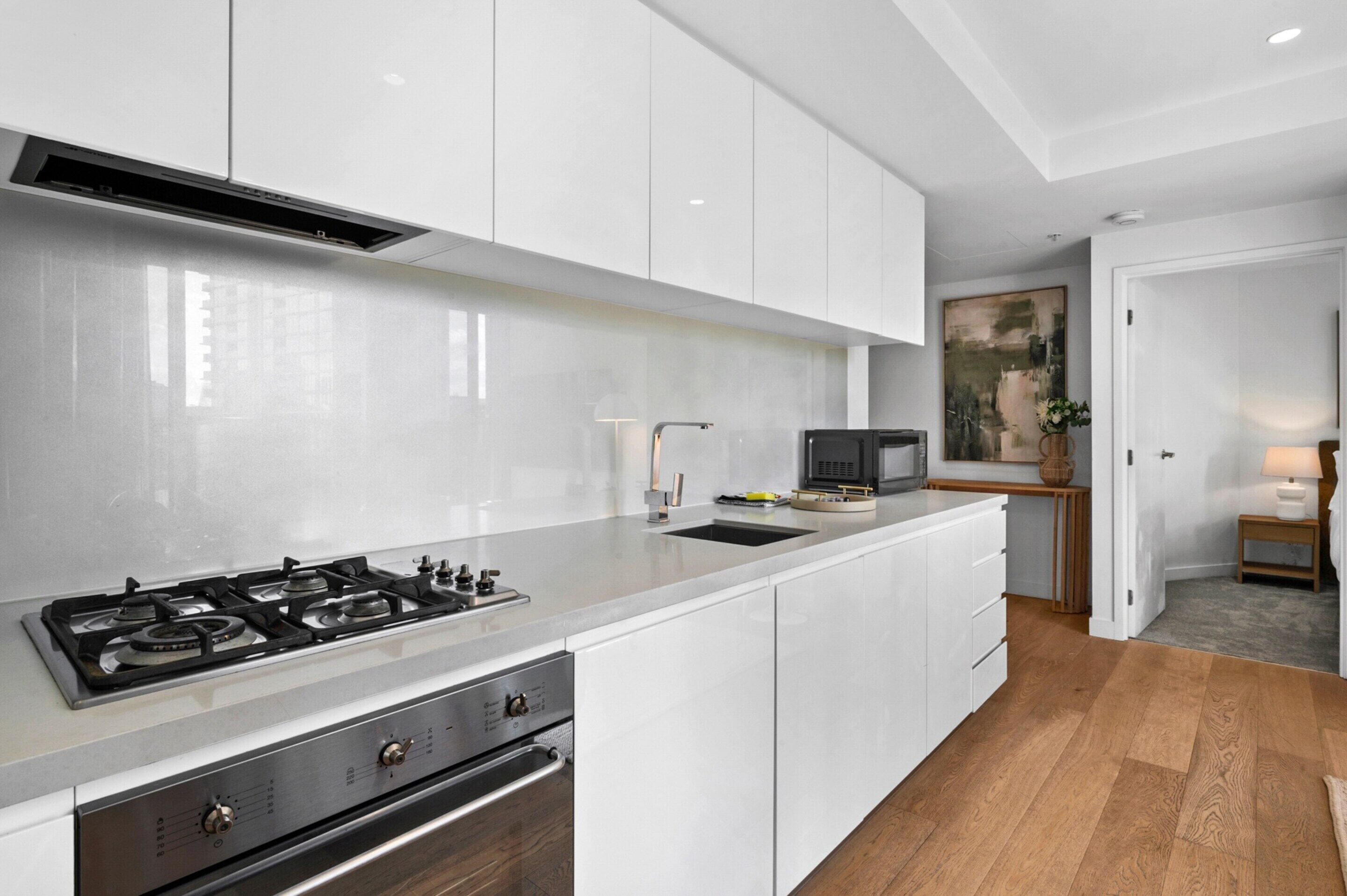 A modern kitchen with white cabinets, a stainless steel stove, and a microwave.