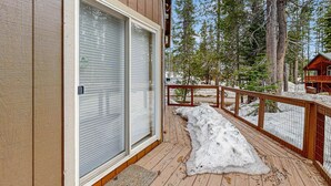 A wooden deck with a glass door leading to a room, surrounded by snow and trees. - Cozy, dog-friendly getaway with wood stove & washer&dryer (Soda Springs)