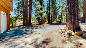 A forested area with a building, a driveway, and a tree with a red post. - Quiet mountain home with game room & fireplace - near scenic trails & ski slopes (Incline Village)