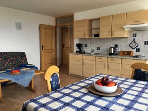 A compact kitchen with wooden cabinets, a tiled backsplash, a coffee maker, and a table with a checkered tablecloth. - Apartment 'Nunnenmayr A' with Mountain View, Shared Garden and Wi-Fi (Tirolo)