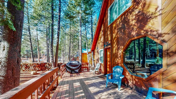 Eine Holzhütte mit einer Terrasse, Sitzmöglichkeiten im Freien und einer überdachten Grillgelegenheit.