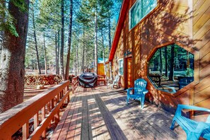 Eine Holzhütte mit einer Terrasse, Sitzmöglichkeiten im Freien und einer überdachten Grillgelegenheit.