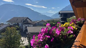 A mountain village with traditional houses, a wooden balcony with flowers, and a clear view of the mountains. - Apartment 'Nunnenmayr B' with Mountain View, Shared Garden and Wi-Fi (Tirolo)