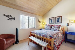 Ein Schlafzimmer mit einem Bett, einer Bank, einem Sessel, einem Schreibtisch und einem Fenster.