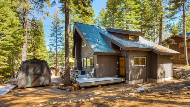 A modern cabin with a sloped roof, a deck, and a small shed in a forested area. - close to beach & skiing with grill, fireplace, deck, & W&D (Tahoma)