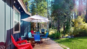 A deck with outdoor furniture, a grill, and a large umbrella.