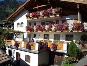 Un edificio a più piani con balconi decorati da fiori, ringhiere in legno e montagne sullo sfondo.