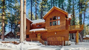 A wooden lodge with a two-story structure, a covered porch, and a garage. - Stunning Large Custom Family Home with Fireplace, Hot tub, Yard, & Views! (South Lake Tahoe)